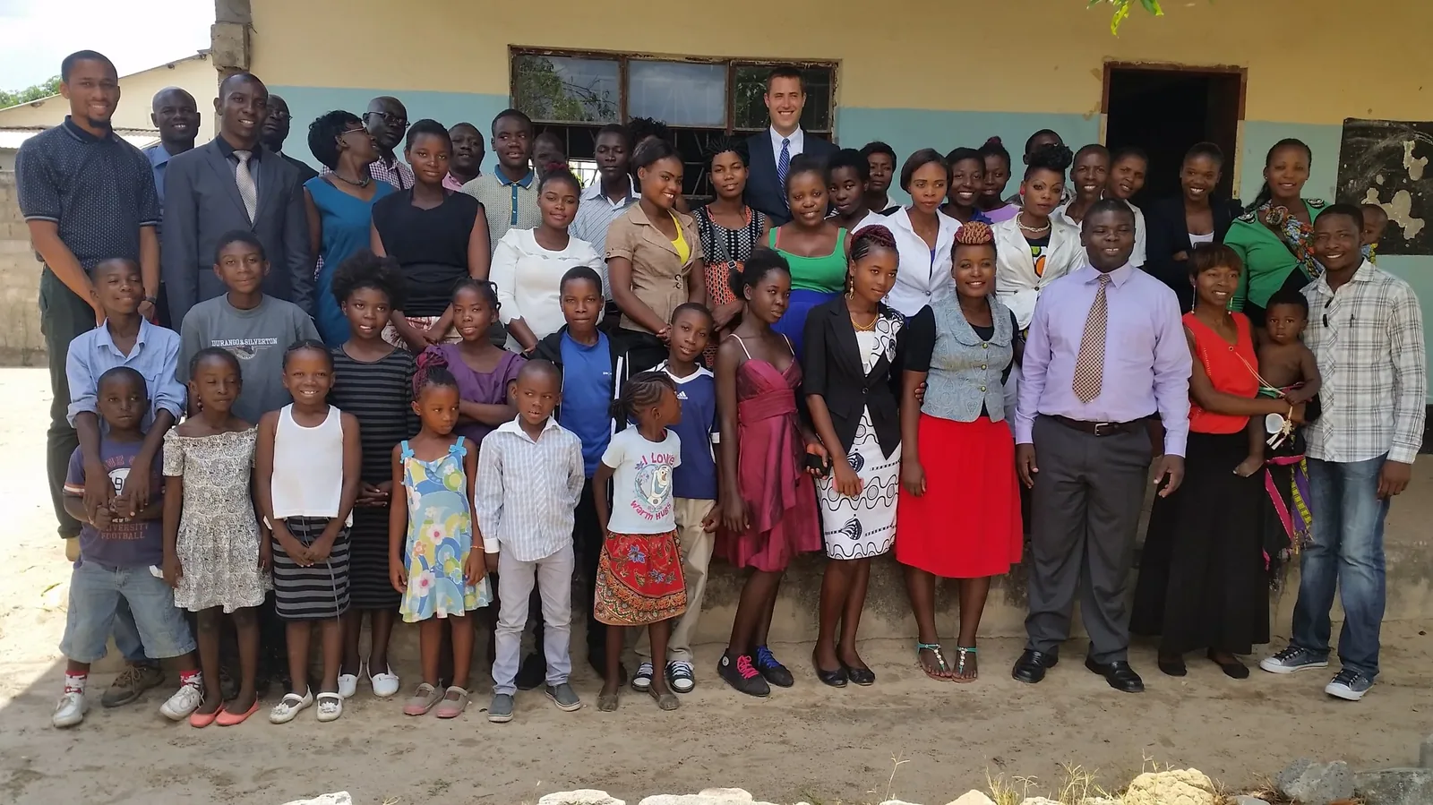 Members of Grace Baptist Church, adults and children, standing together on the sand outside the church