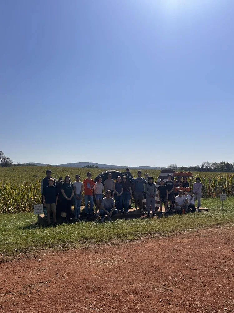 Youth group standing at the edge of a corn maze field on a clear autumn day
