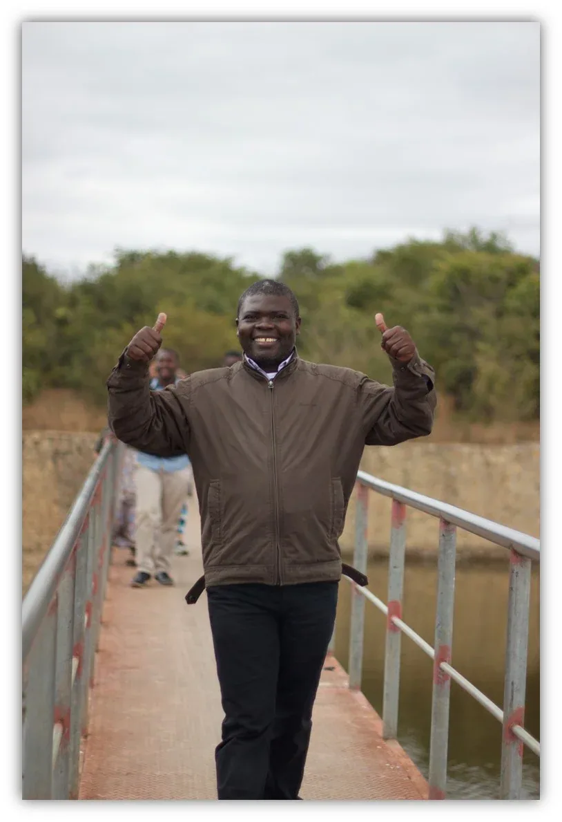 Manasseh Kaonga standing on the walkway of the baptismal pool with his arms raised