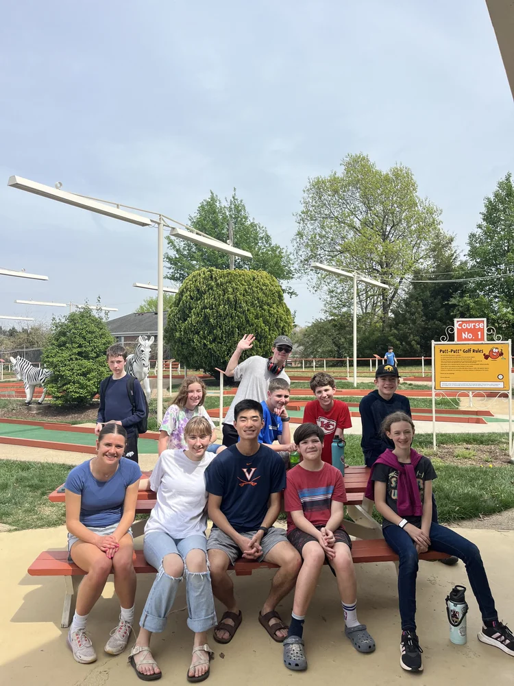 Youth group sitting together at a picnic table at a mini golf course