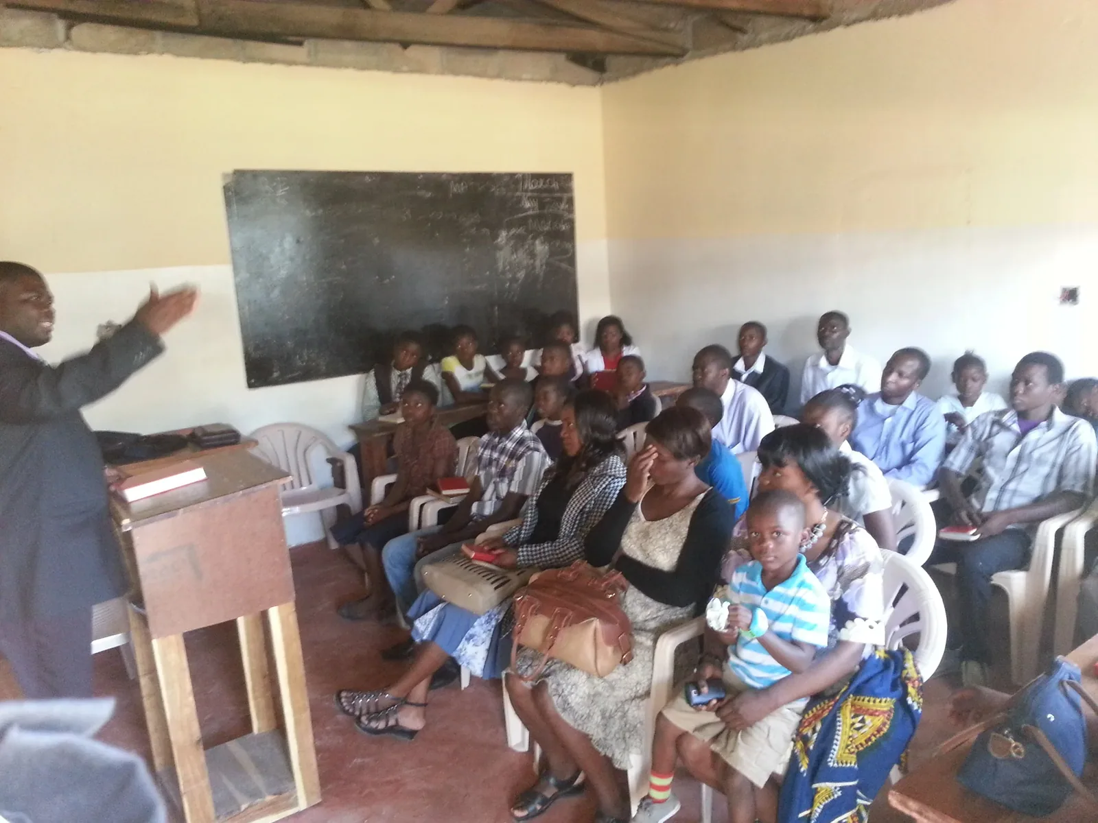 A teacher at a chalkboard leading a Sunday school class of children and adults