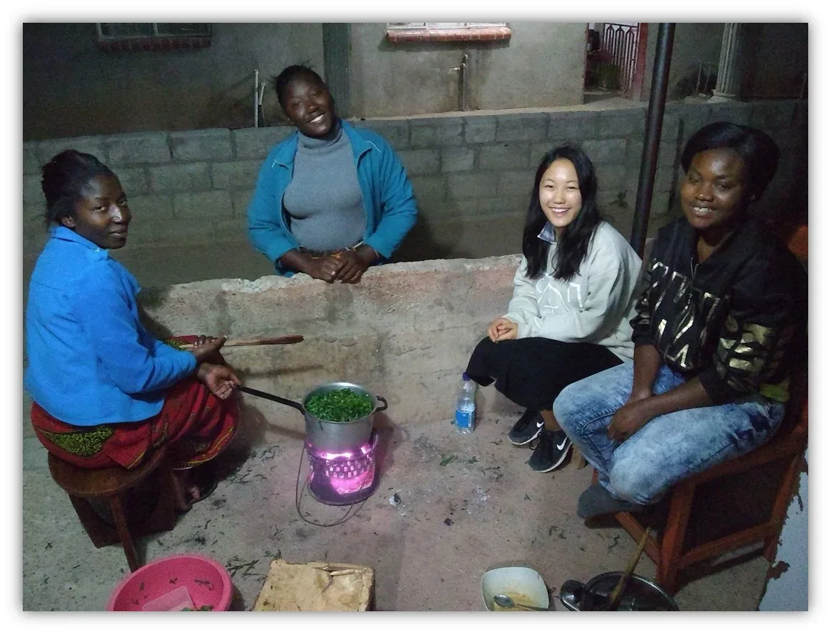 Women cooking together over an open fire in a courtyard