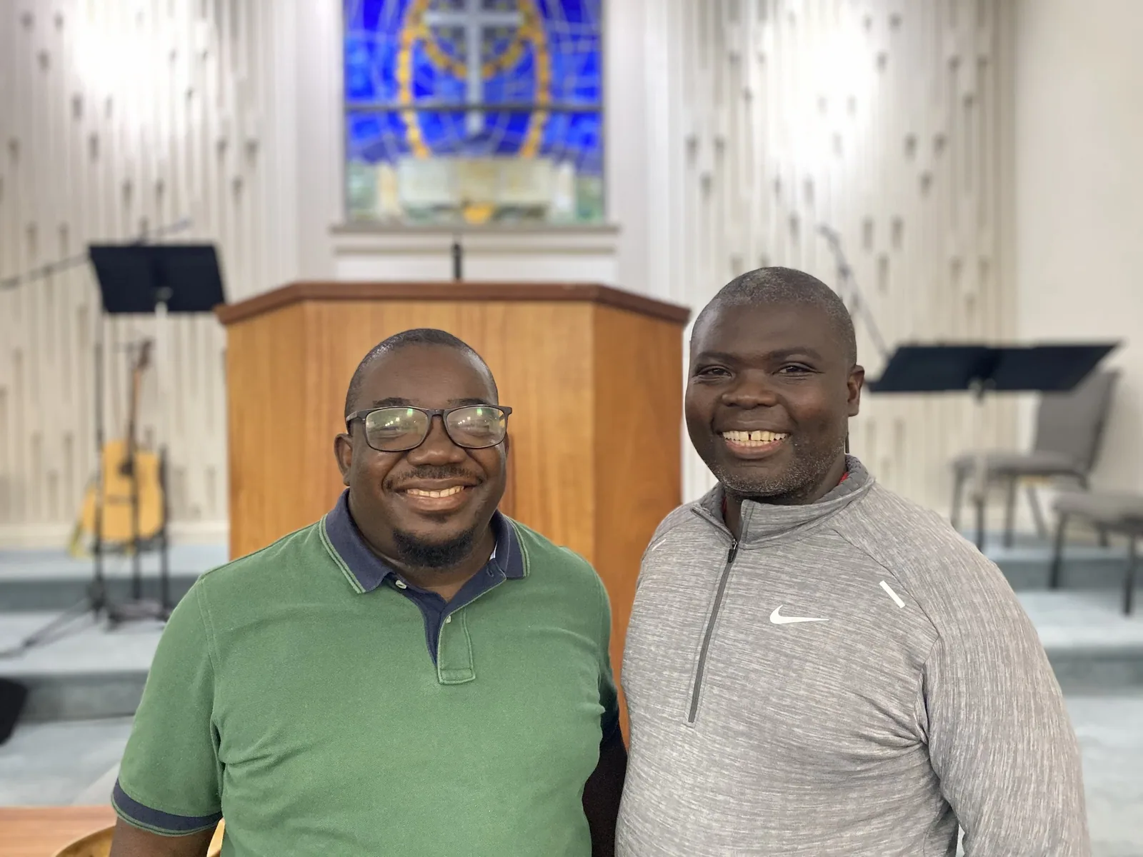 Million Kambuli and Manasseh Kaonga standing together at the front of a church sanctuary