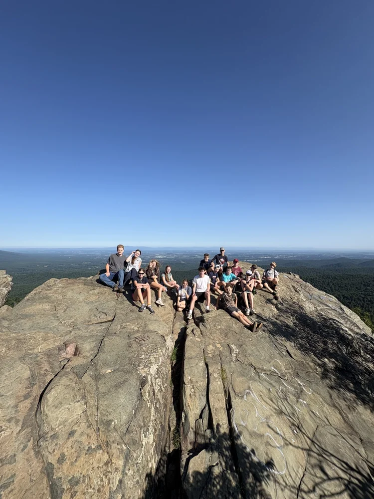 Youth group resting on a rocky mountaintop overlook above the Virginia foothills