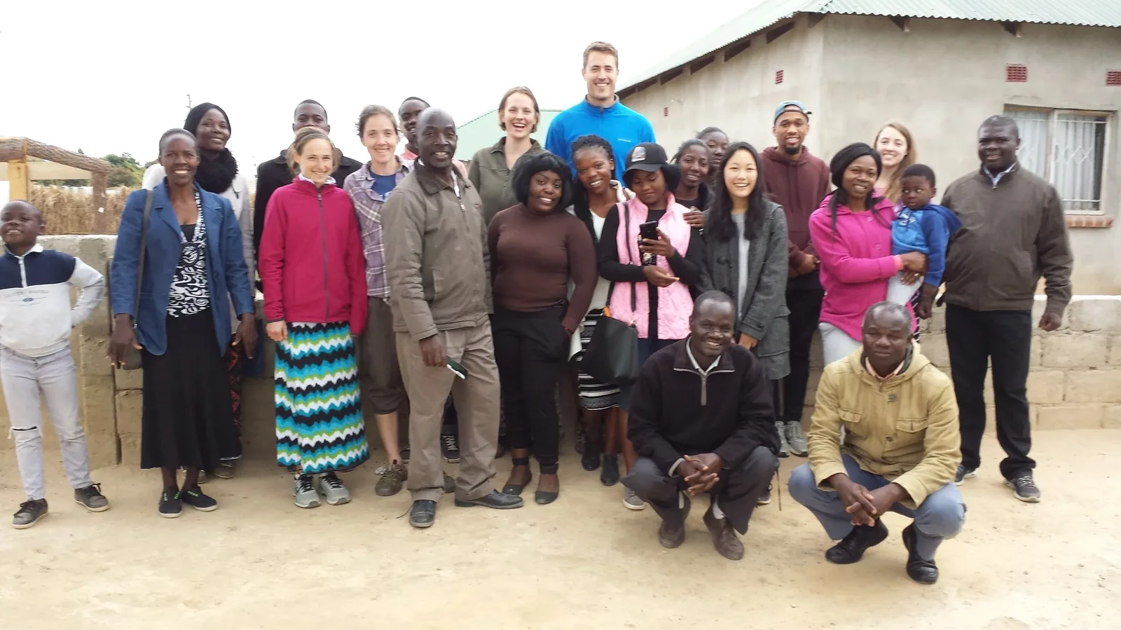 A large group of church members and visitors standing together outside a brick church in Zambia