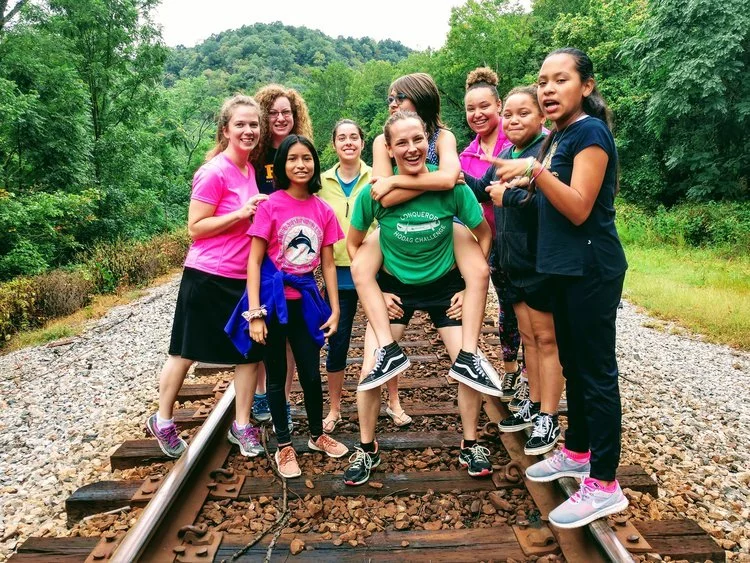 Girls from the Southwood ministry laughing together on a railroad track in the woods