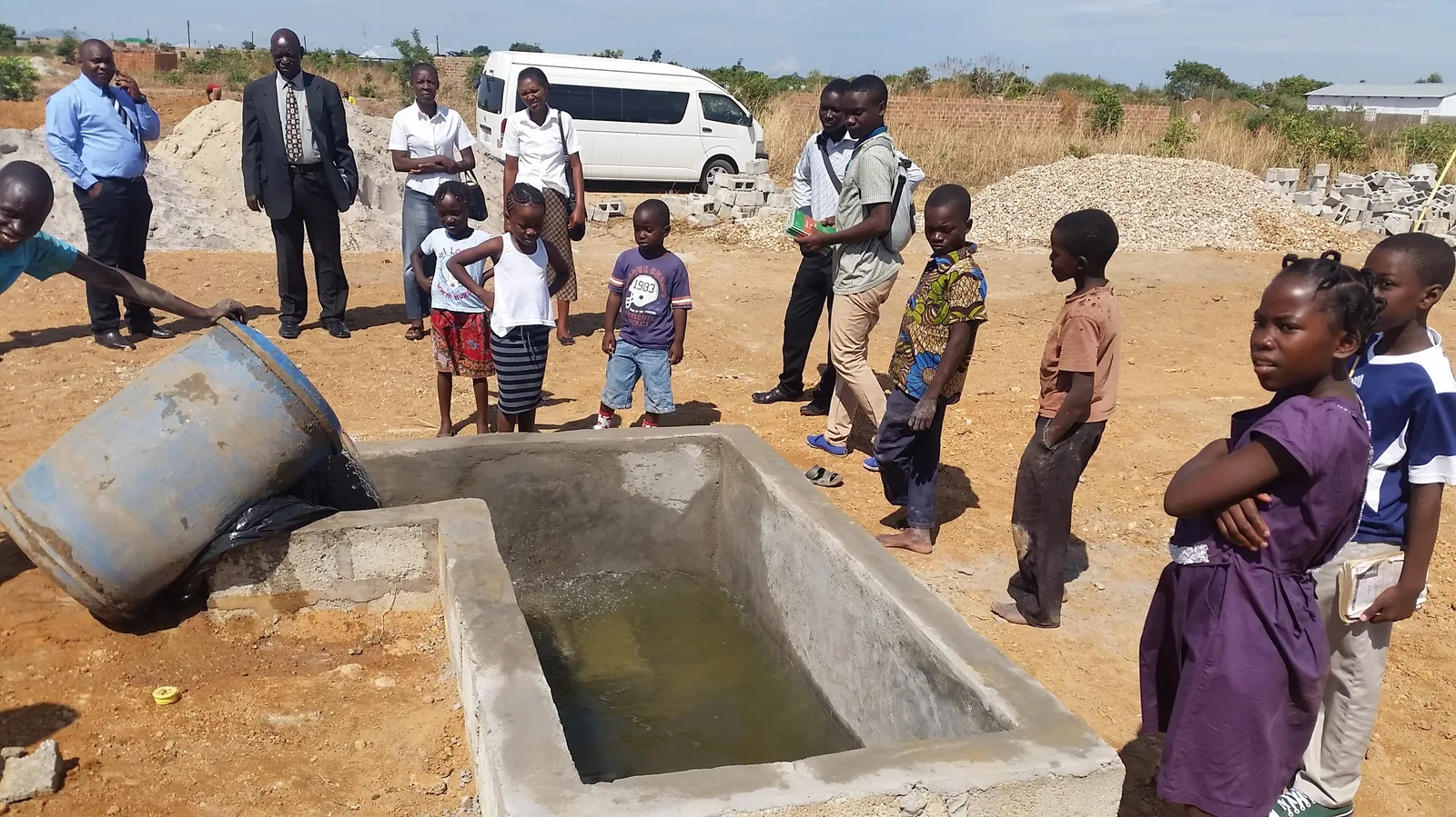 Church members and children gathered around a newly built outdoor baptismal pool