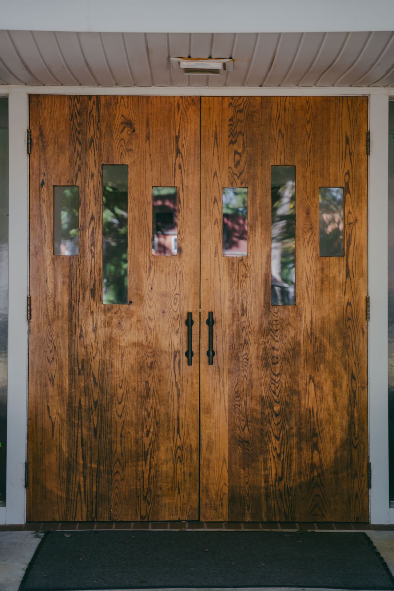 The wooden front doors of Jefferson Park Baptist Church under the entrance portico