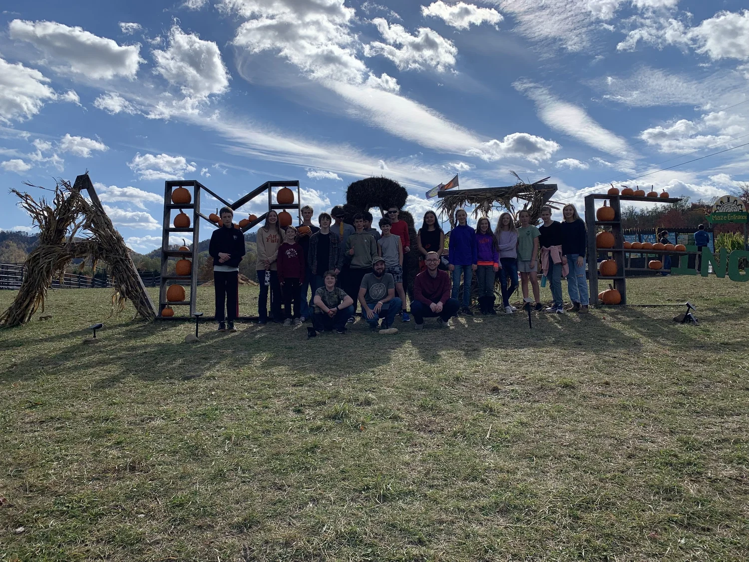 Youth group posing in front of a pumpkin display at a fall corn maze